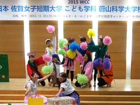 写真；ステージ上でチアポンポンを持ってポーズをつけている生徒たち