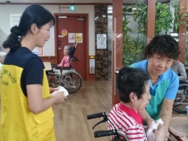 写真：介護士と車椅子の女性、実習体験をしている生徒